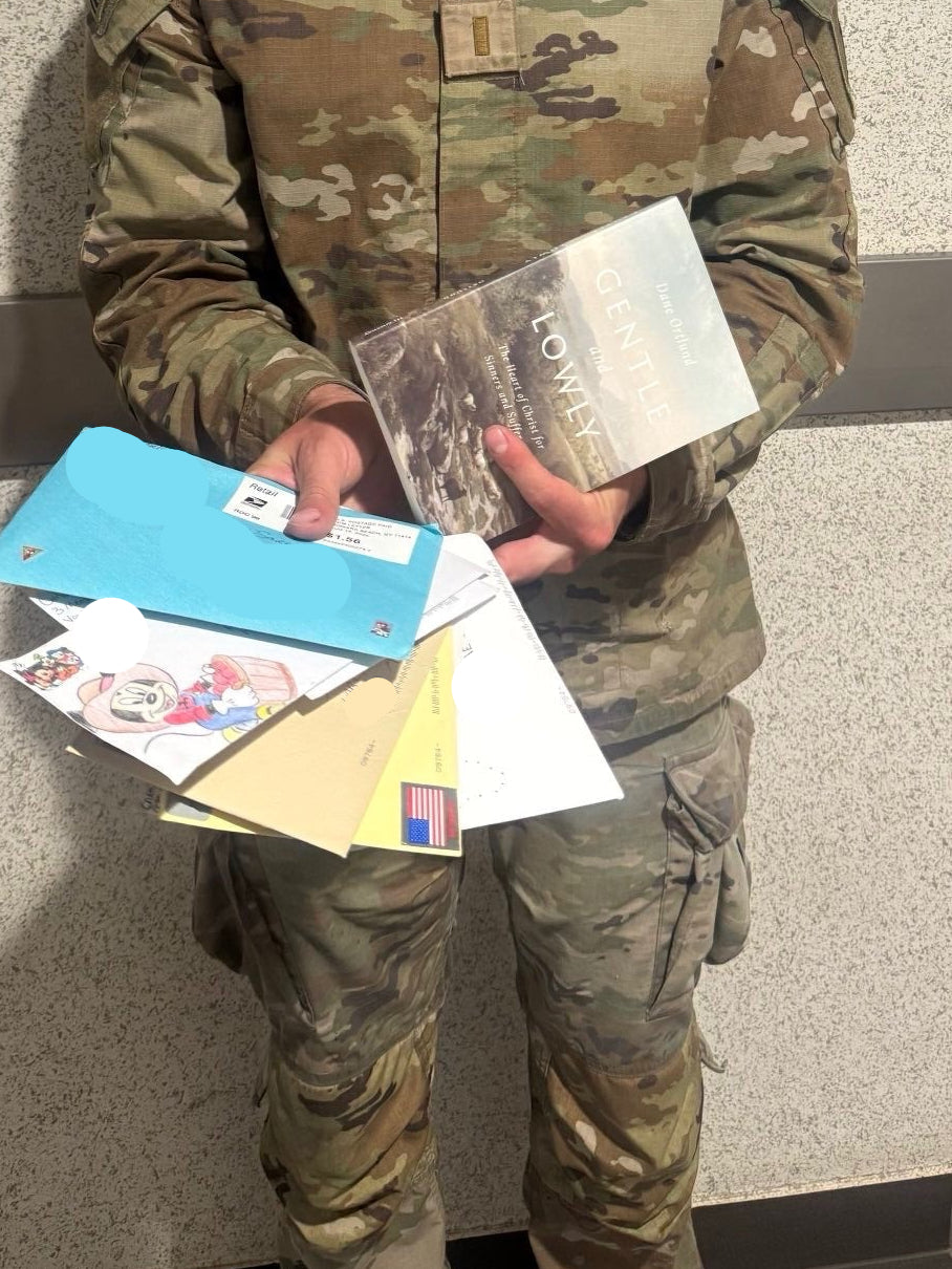 Person in military uniform holding letters against a tiled wall.